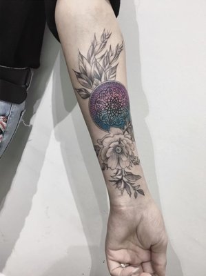  Tatouage mandala sur le bras et coloré en bleu et rose